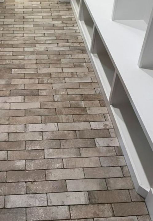 Mudroom with rustic brick paver tile floor laid diagonally beside white built-in bench cubbies