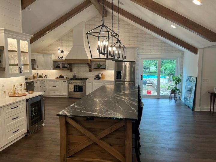 Farmhouse kitchen with white brick tile run up the vaulted gable wall, wood beams and black soapstone island
