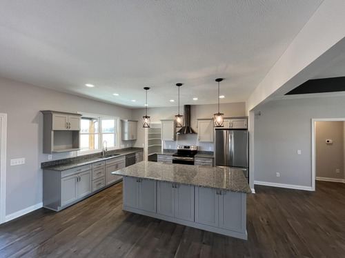Dark hardwood plank flooring in a remodeled kitchen with gray cabinets and granite island