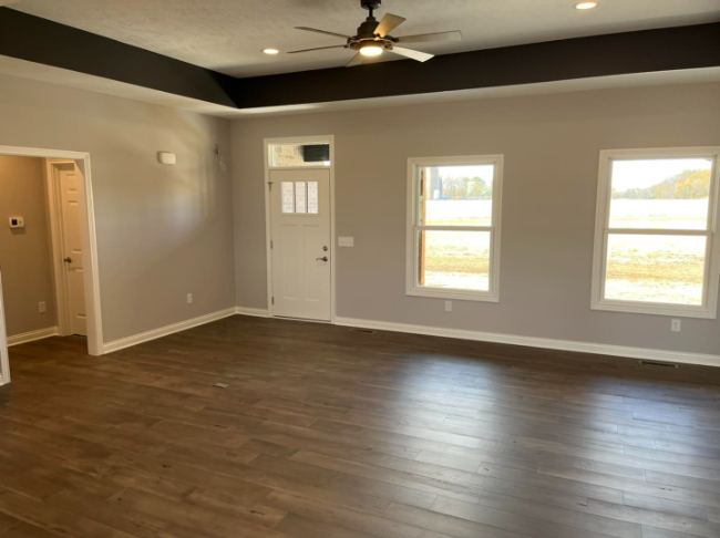 Dark brown luxury vinyl plank flooring in a bright living room with tray ceiling
