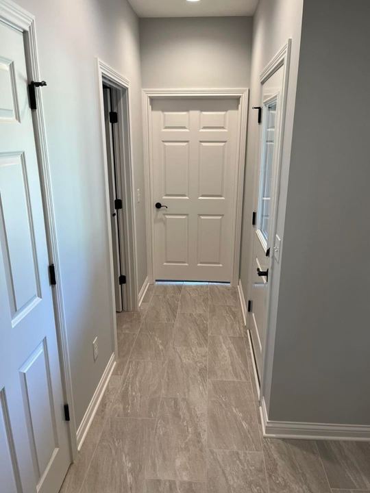 Back hallway with greige wood-look plank tile flooring, gray walls and white six-panel doors
