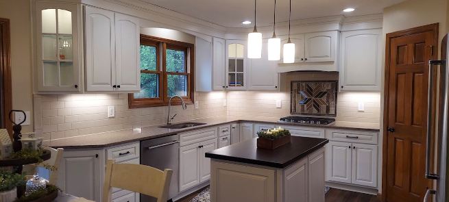 Remodeled kitchen with white subway tile backsplash and decorative wood-look mosaic accent above the cooktop