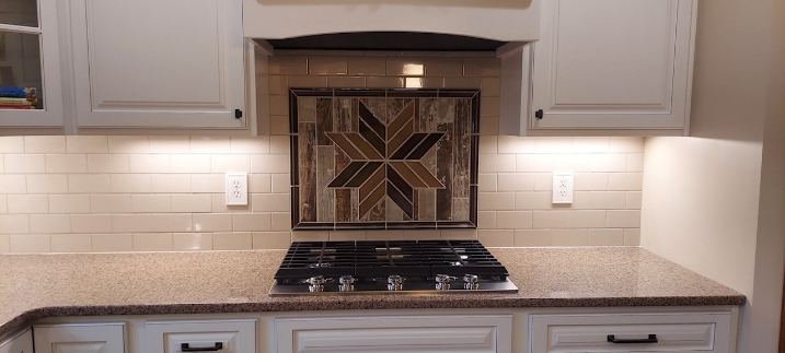 Cream subway tile backsplash with wood-look mosaic star medallion above the cooktop