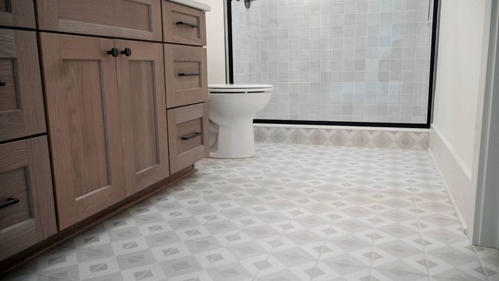 Bathroom with gray and white geometric patterned tile floor, square-tile shower and rustic oak vanity